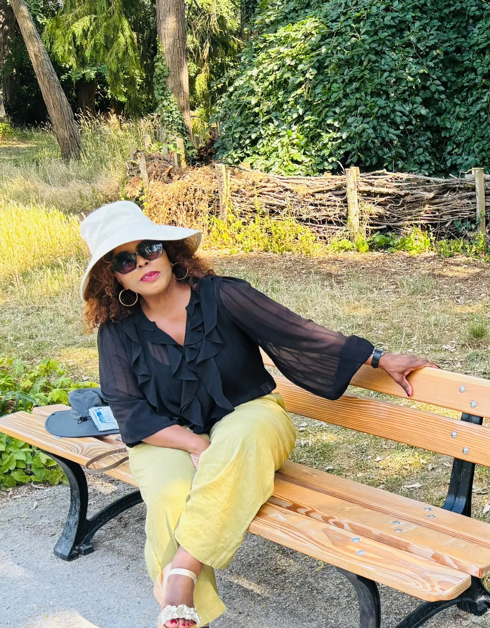 Dr. Alina relaxing on a wooden bench among trees in France